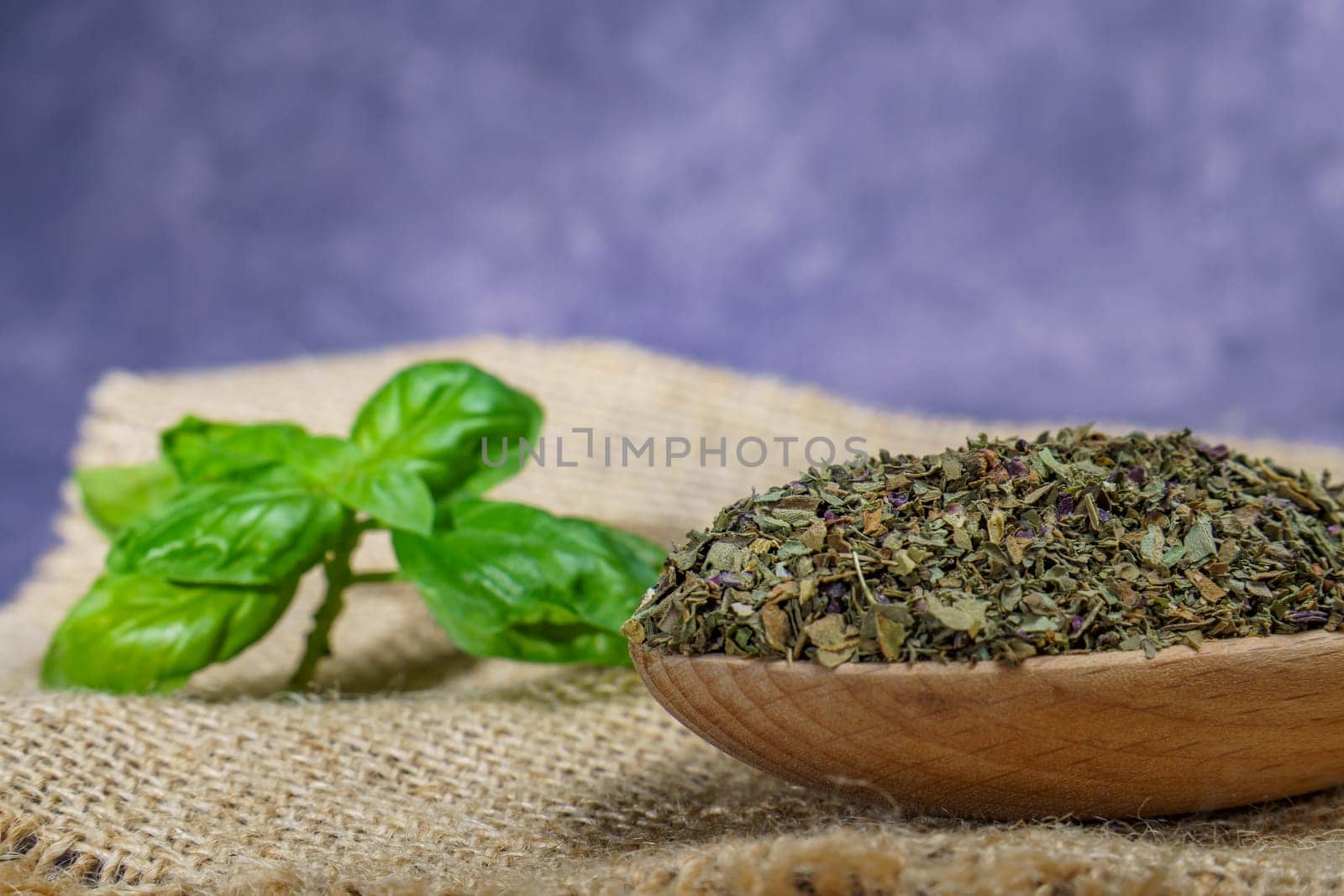 dried basil ground in a wooden spoon by joseantona