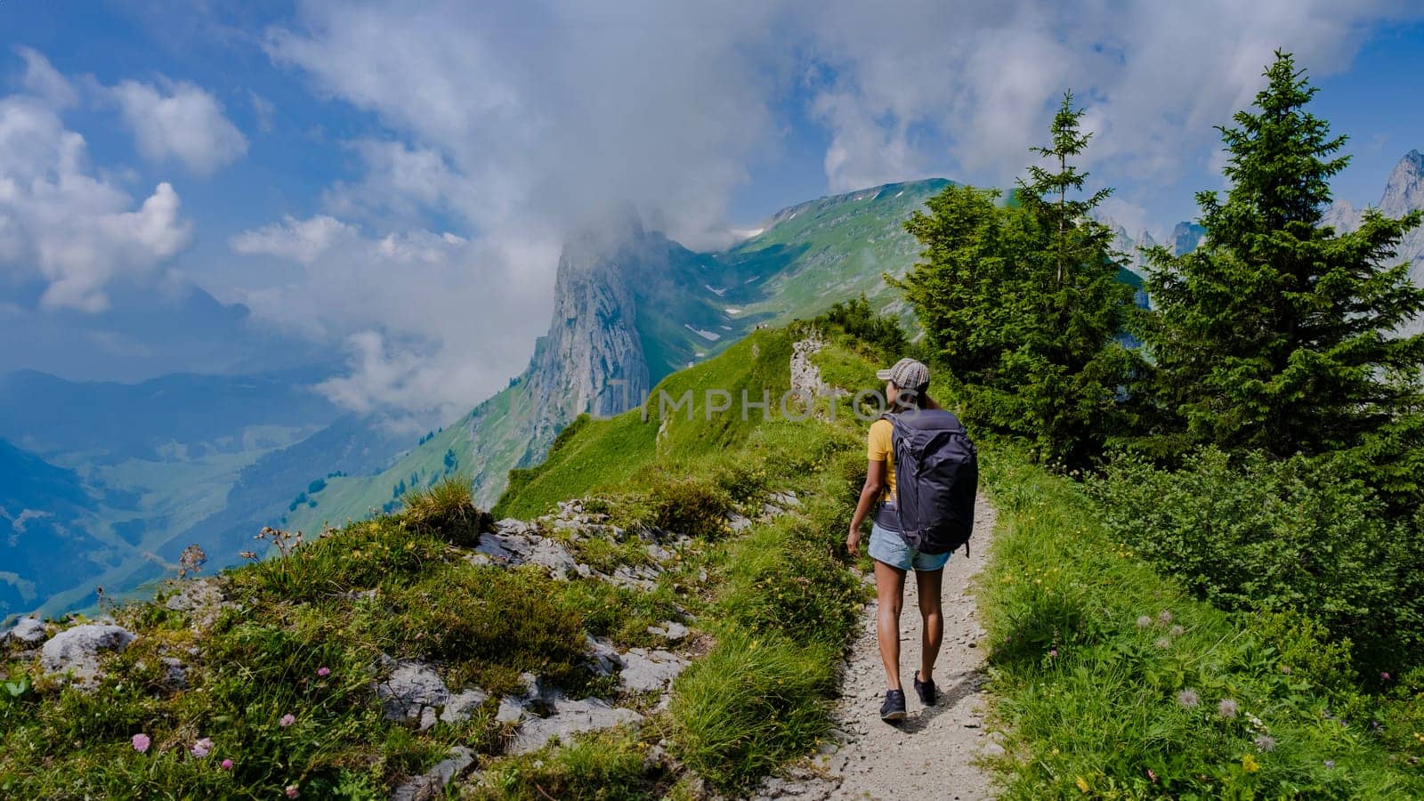 women hiking in the Swiss Alps mountains during summer vacation with a backpack and hiking boots. woman walking on the Saxer Lucke path in Switzerland during summer