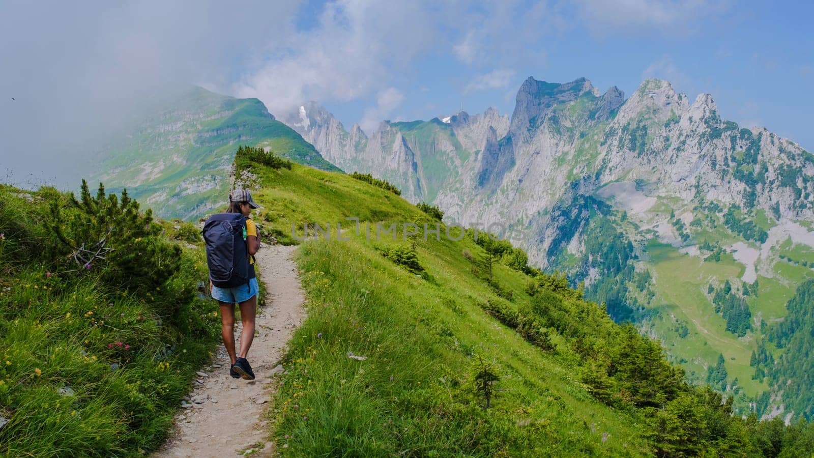 women hiking in the Swiss Alps mountains at summer vacation with a backpack and hiking boots by fokkebok