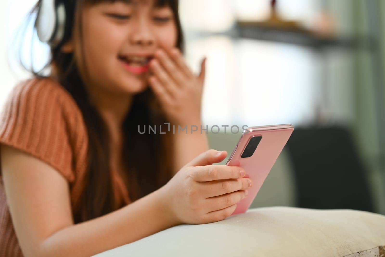 Cute preteen girl using mobile phone having fun with apps and checking social media by prathanchorruangsak