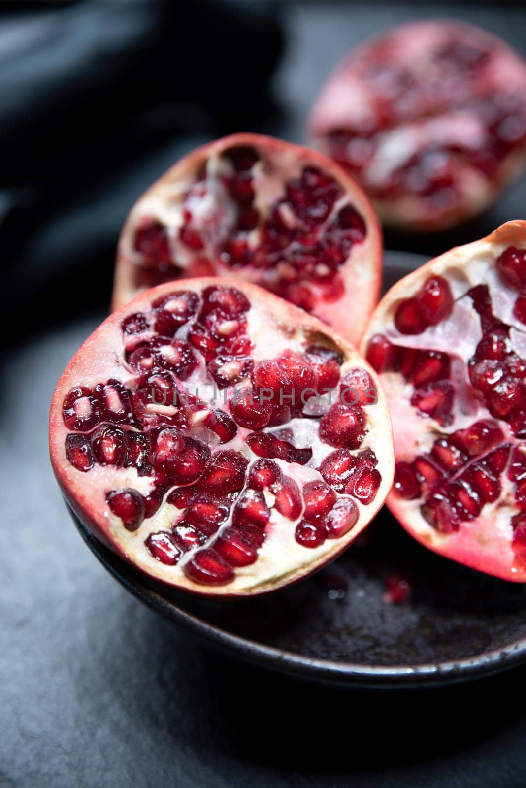 Ripe cut pomegranate on a slate plate. Red and dark colors composition