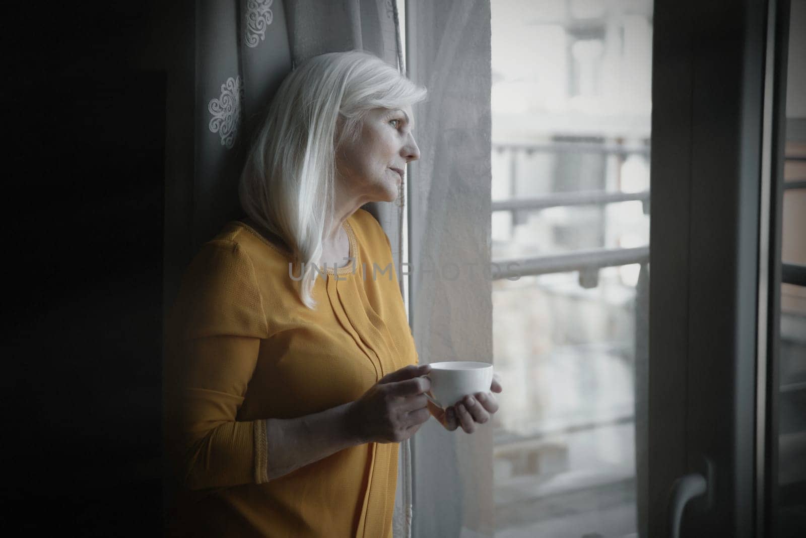 Depressed senior woman near window by simpson33