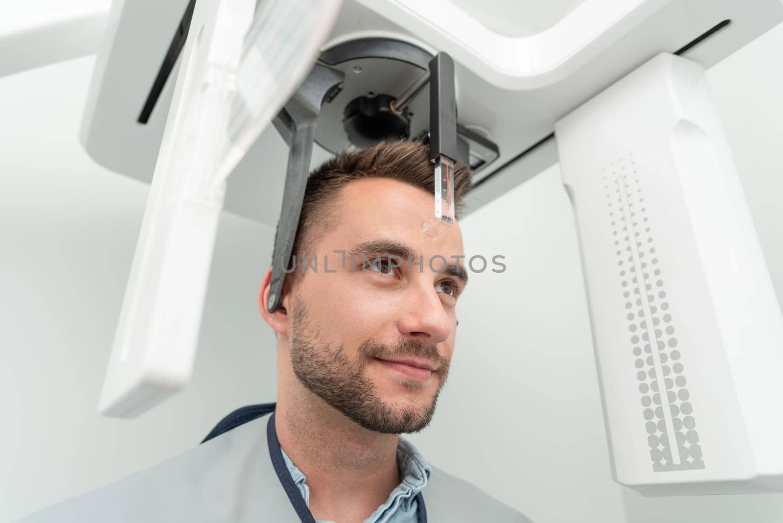 Handsome man patient standing in x-ray machine. Panoramic radiography at professional dental clinic.