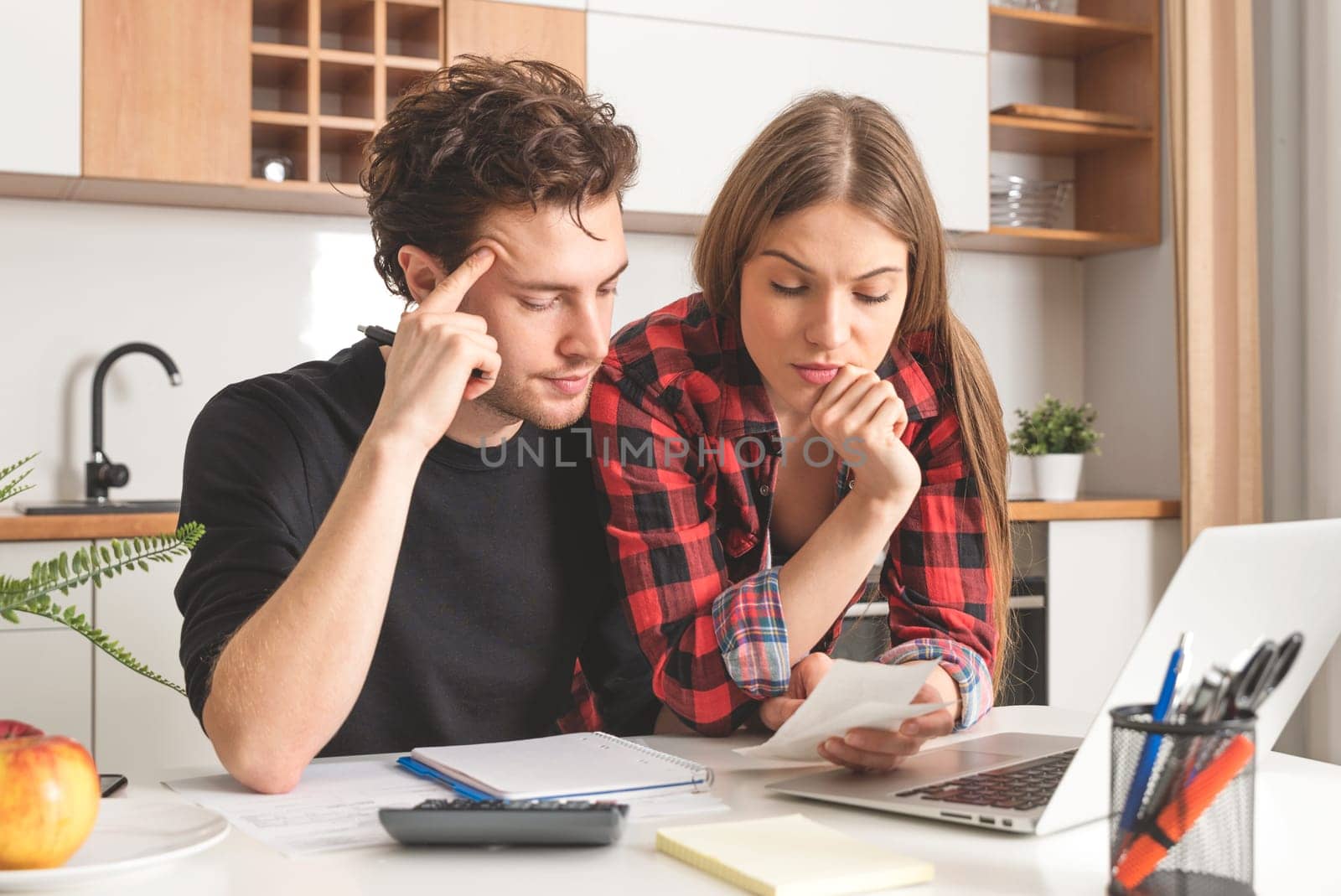 Young couple calculating money at home. Financial revision, home budget concept