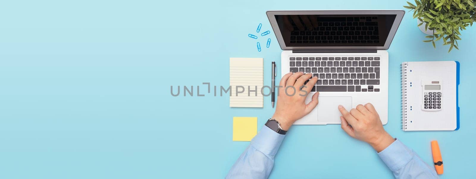 Workspace with laptop, office supplies. Man working on stylish table desk. Image with copy space on blue background