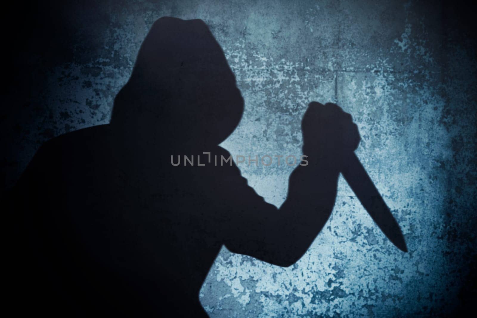 Silhouette criminal holding knife on dirty background