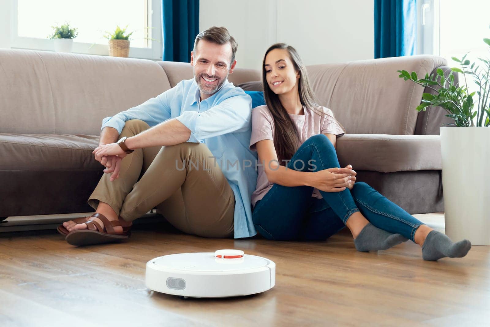 Couple on the floor, robot vacuum cleaner cleaning by simpson33