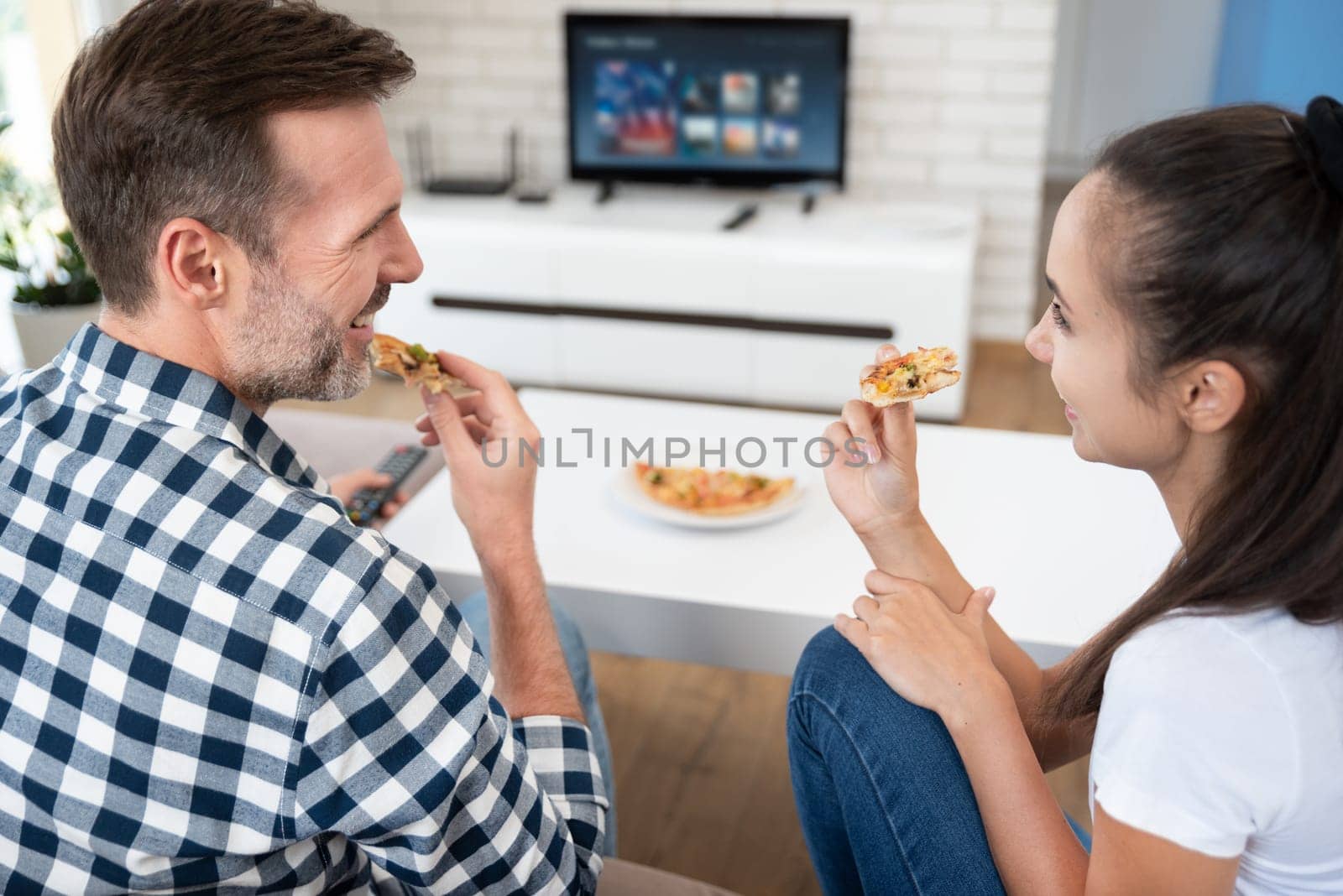 Couple watching TV while eating pizza by simpson33