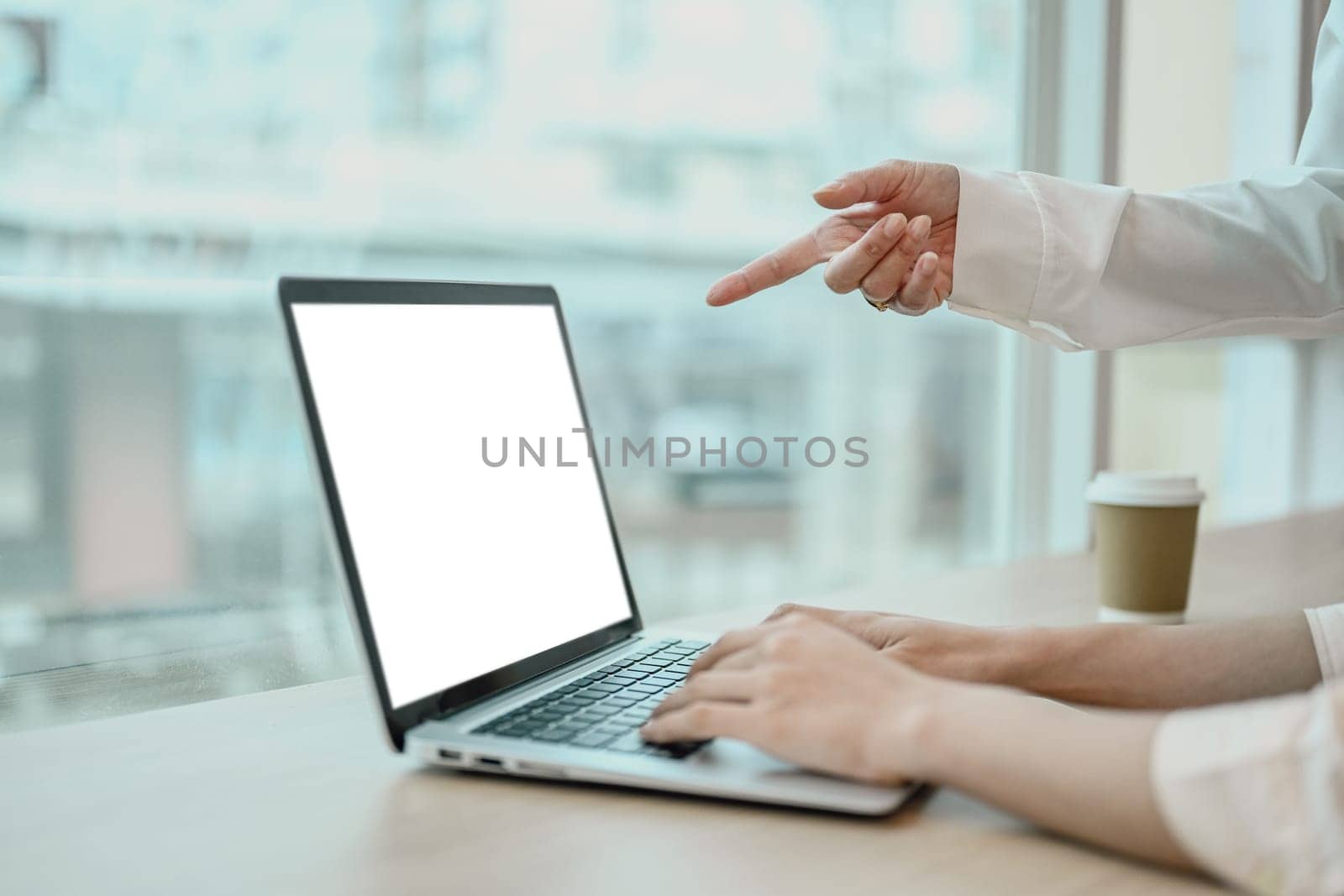 Cropped image of business colleagues using laptop computer, collaborating on project at office by prathanchorruangsak