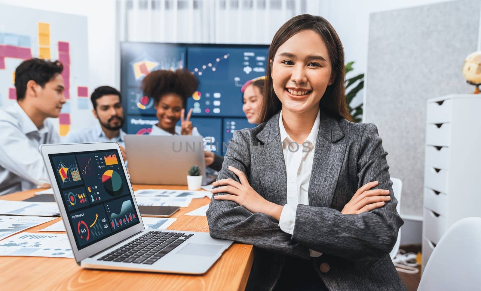 Portrait of happy young asian businesswoman with group of office worker on meeting with screen display business dashboard in background. Confident office lady at team meeting. Concord