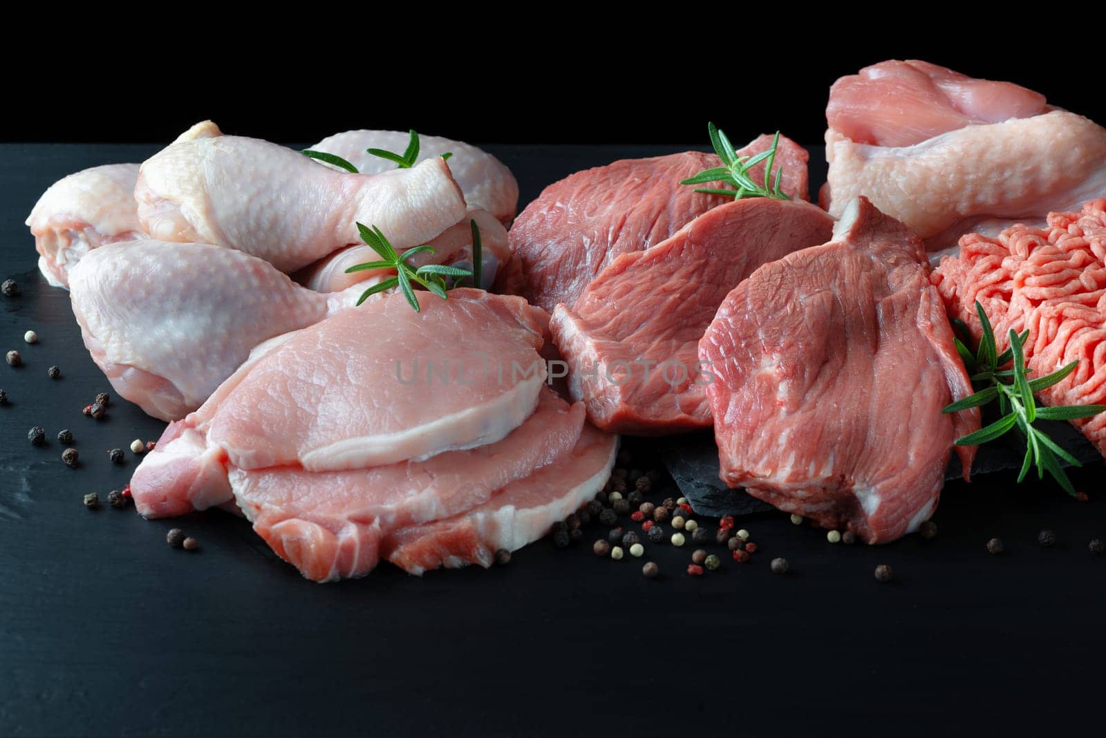 Different types of raw meat - beef, pork, lamb, chicken on a wooden board.