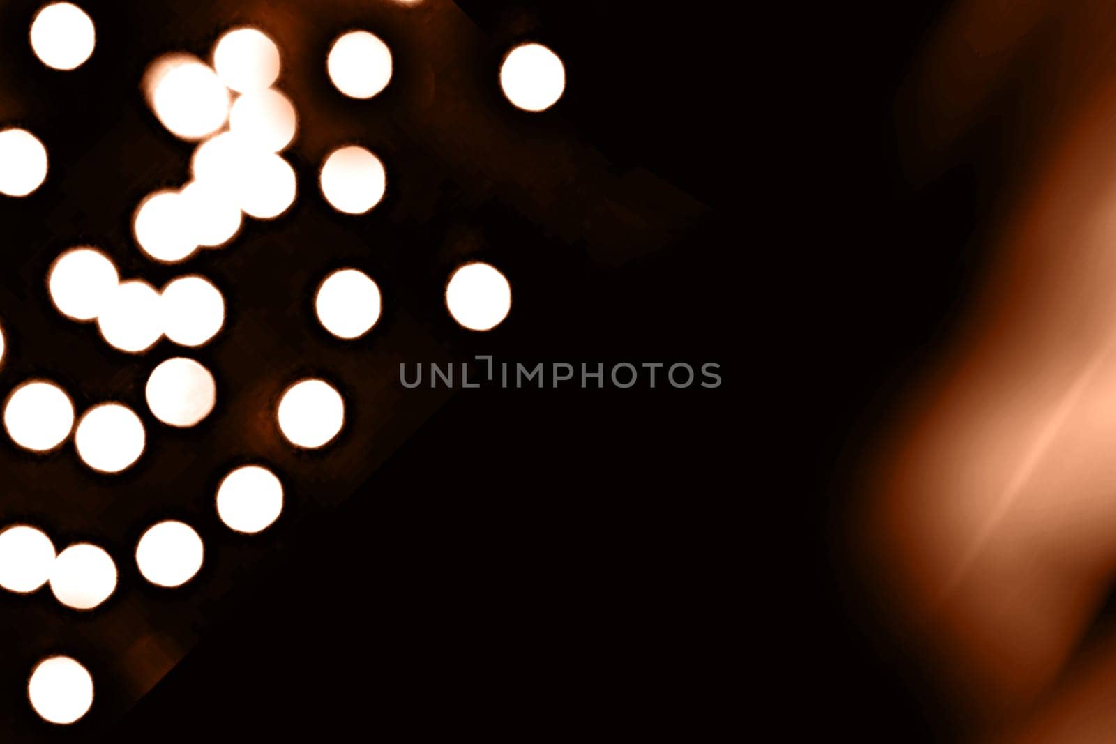 Blurry garland lights on a dark background. Festive Christmas and New Year background. Soft focus. Image toned in color of the year 2024 - Peach Fuzz by Annu1tochka