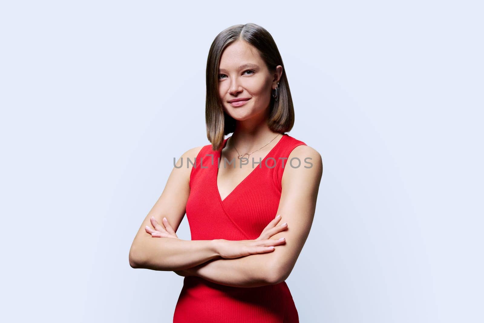 Portrait of young confident woman in red on white studio background by VH-studio