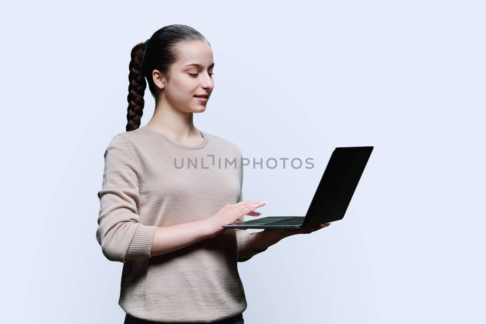 Teen girl high school student using laptop looking at computer on white background by VH-studio