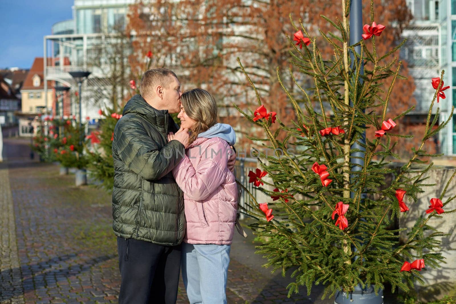 couple in love A guy and a girl hugging on the street of the old European town of Bietigheim-Bissingen in Germany on Christmas Eve. The city streets are decorated with Christmas trees and New Year's decorations. Capturing Love in the Glow: Couple Embracing in the Enchanting Streets of Bietigheim-Bissingen, Germany, on Christmas Eve by Andrii_Ko