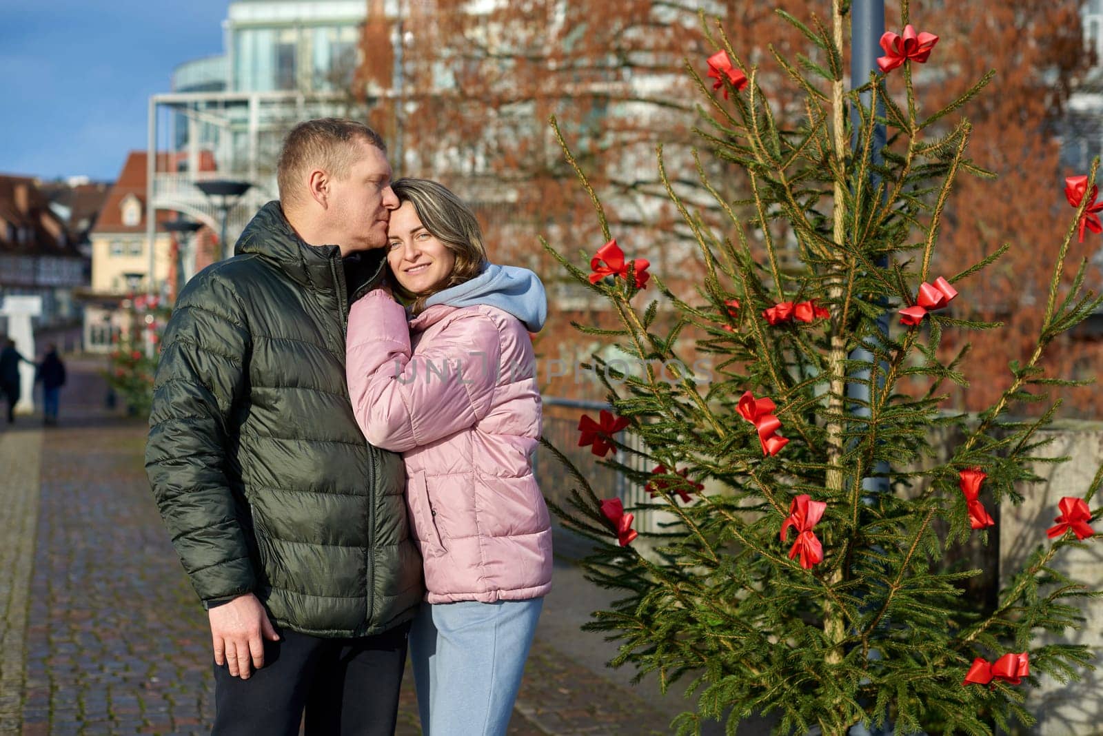 couple in love A guy and a girl hugging on the street of the old European town of Bietigheim-Bissingen in Germany on Christmas Eve. The city streets are decorated with Christmas trees and New Year's decorations. Capturing Love in the Glow: Couple Embracing in the Enchanting Streets of Bietigheim-Bissingen, Germany, on Christmas Eve by Andrii_Ko