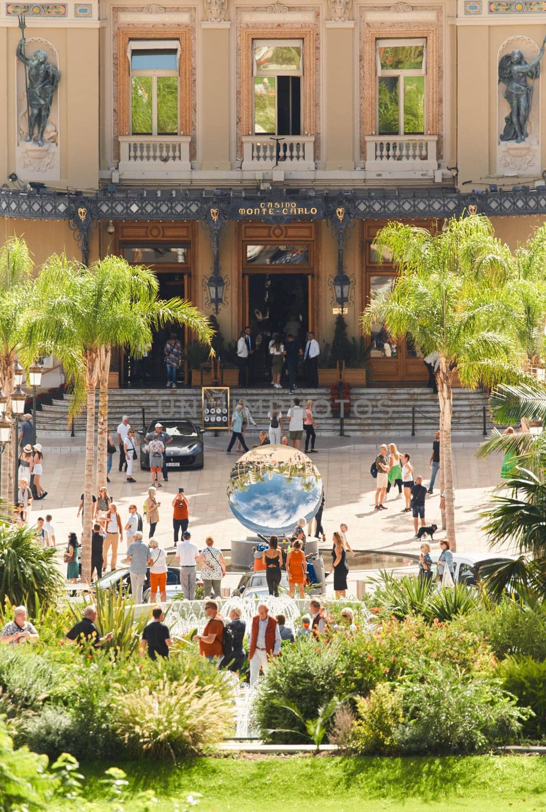 Monaco, Monte-Carlo, 21 October 2022 - Square Casino Monte-Carlo at sunny day, wealth life, tourists take pictures of the landmark, pine trees, blue sky. High quality photo