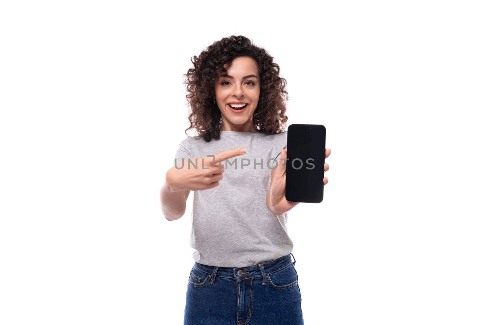 well-groomed european woman with natural black curly hair in a gray basic t-shirt on a white background.