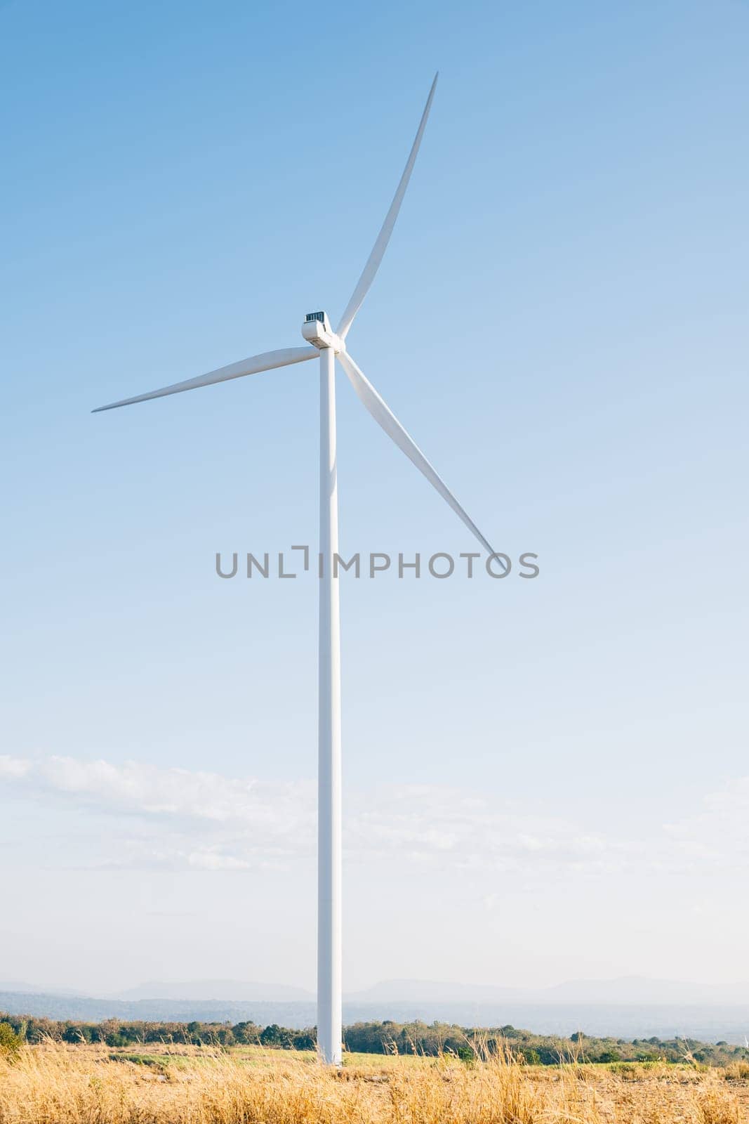 A winter windmill farm on a mountain harnesses clean wind energy with efficient turbines. Innovative technology drives sustainable development under the vast blue sky.