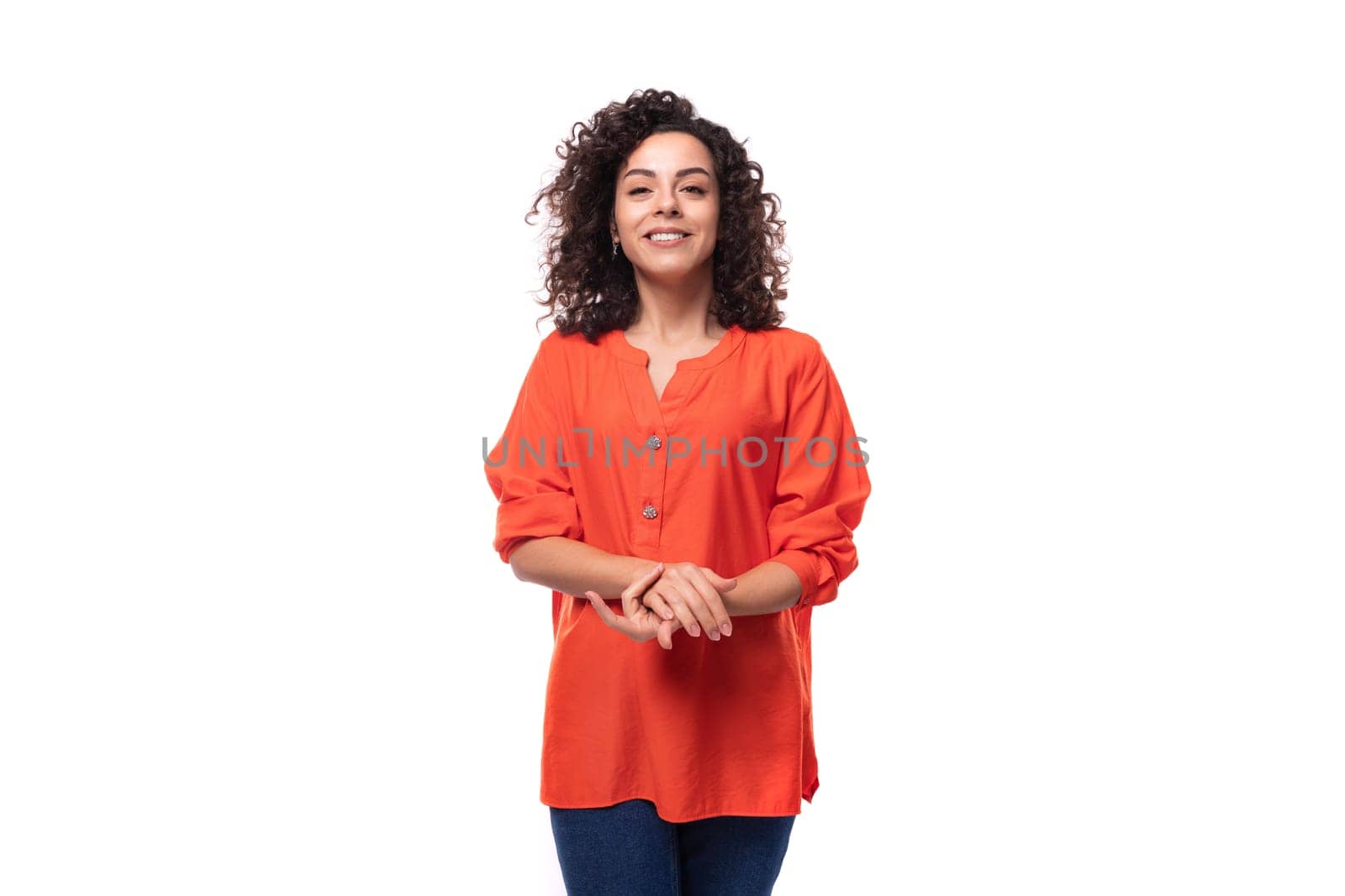 portrait of a bright young caucasian brunette woman with curly hair dressed in an orange shirt.