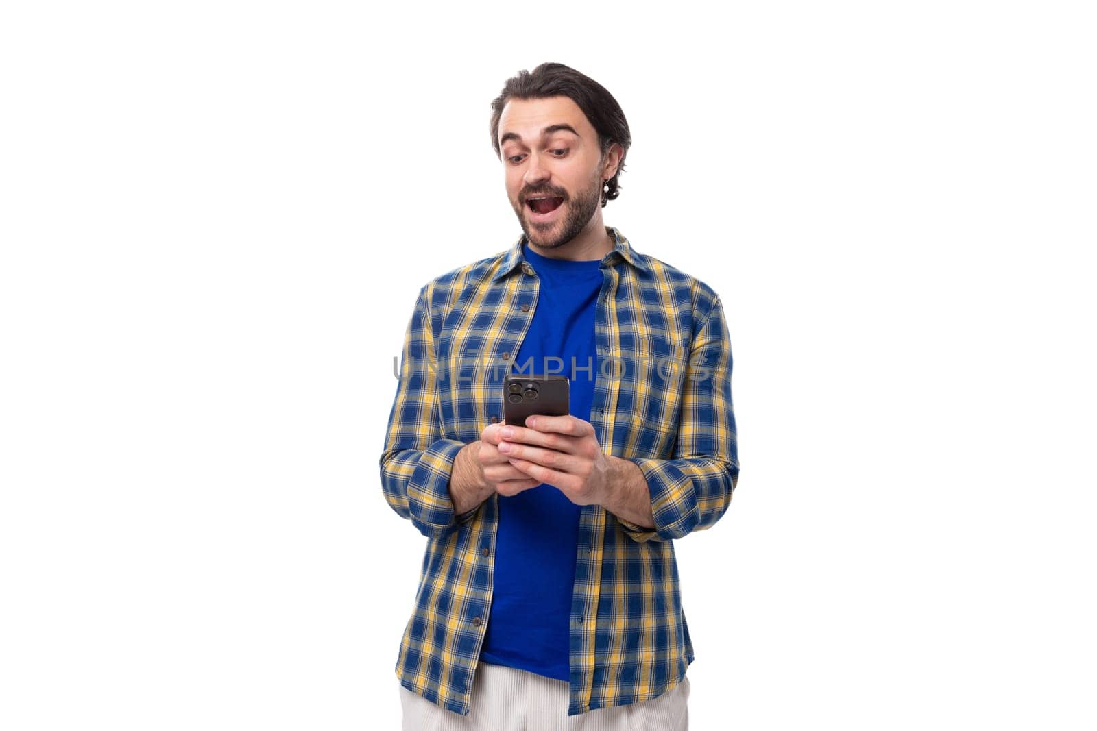 handsome young European brunette man with a beard actively uses a mobile phone.