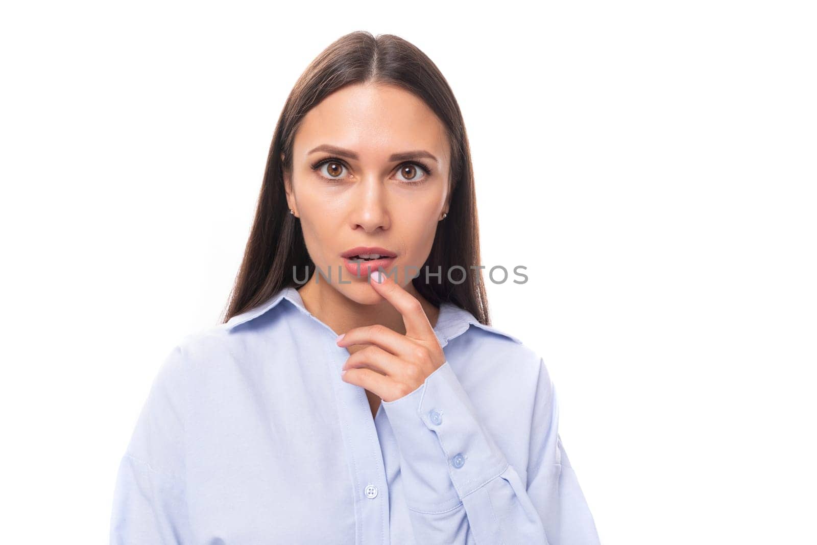 portrait of a young beautiful european model woman with long black hair dressed in a blue blouse on a white background with copy space by TRMK