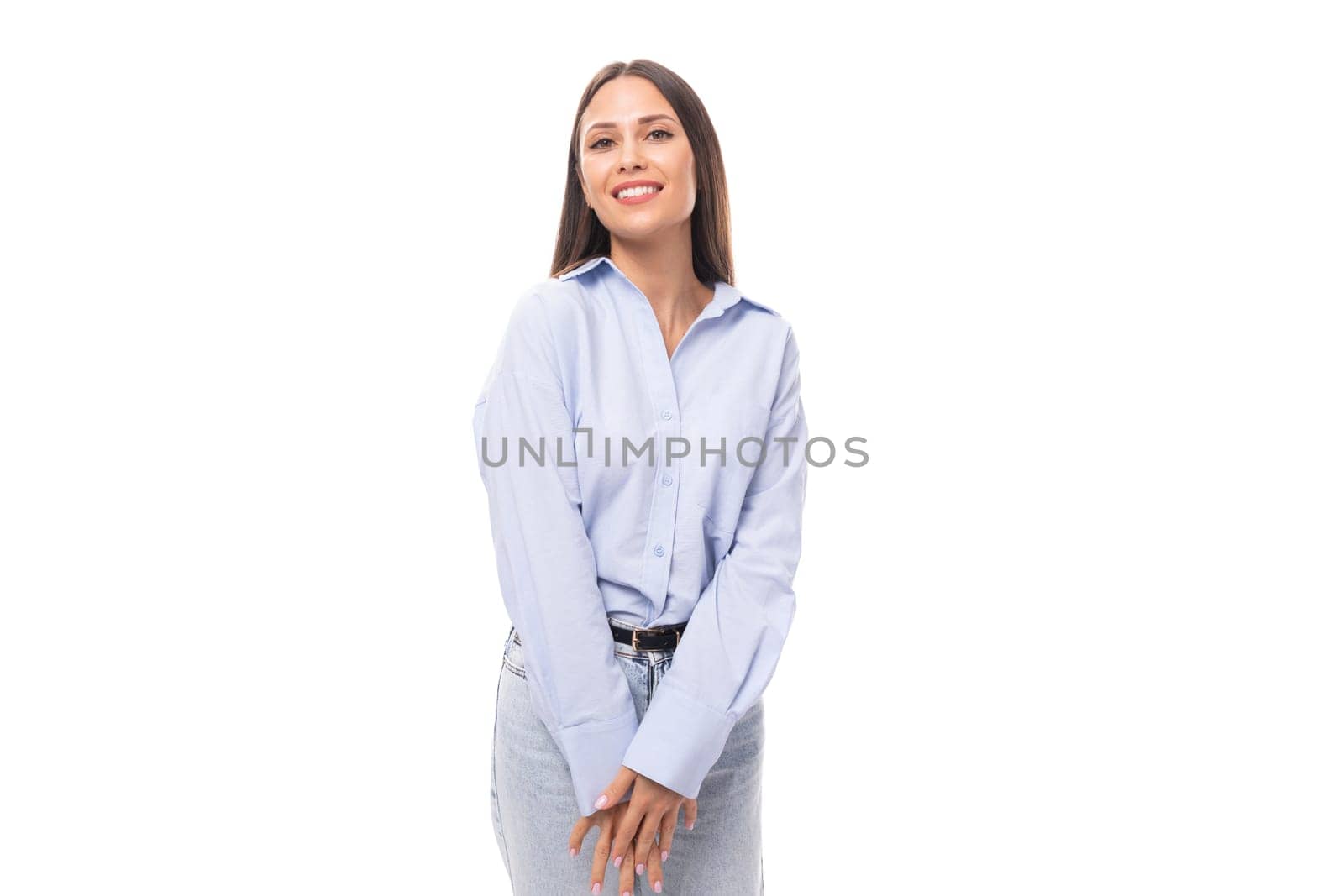 close-up of a young beautiful european brunette business woman with light makeup in a light blue shirt smiling with teeth on a white background with copy space.