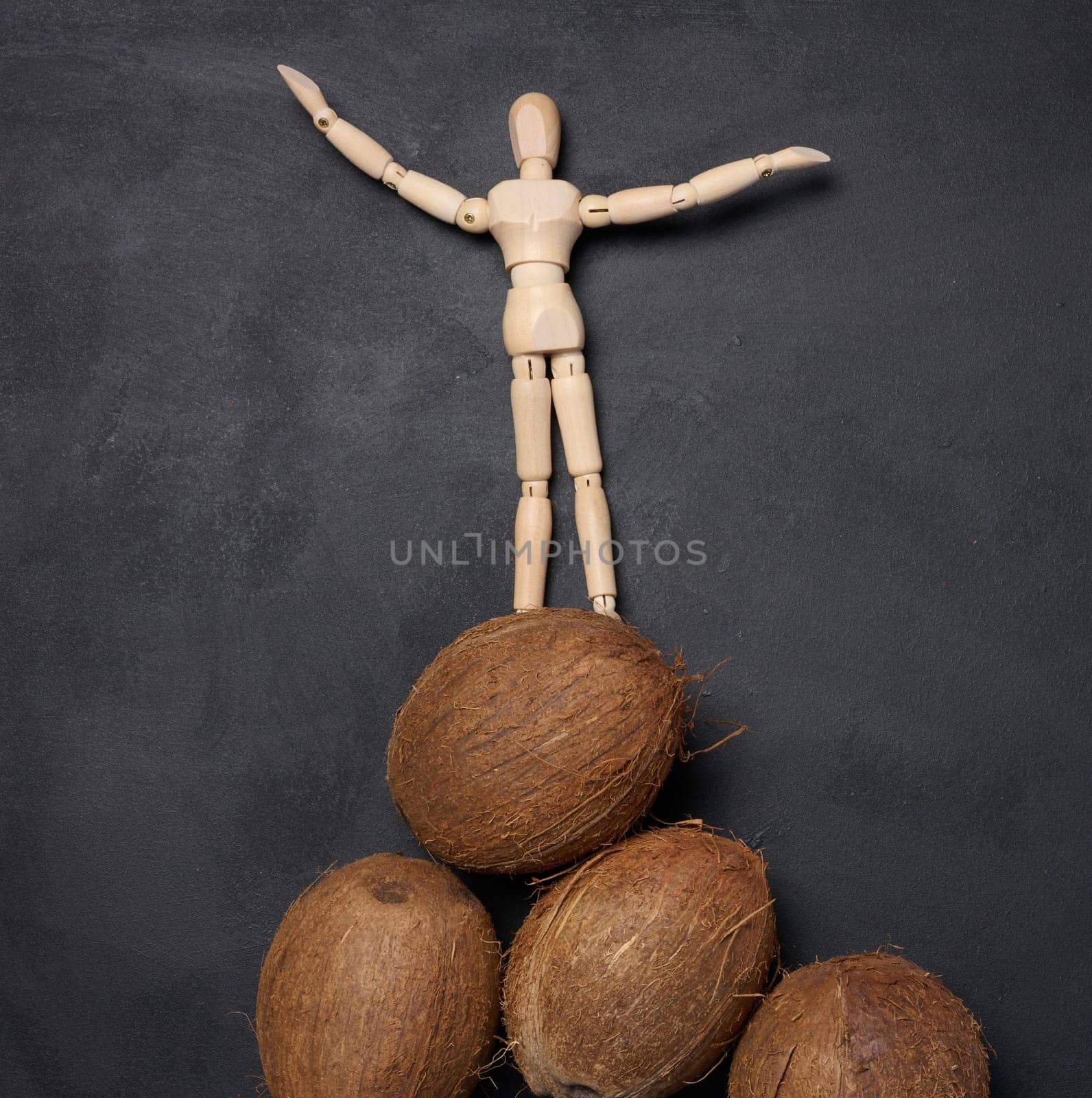 Wooden mannequin stands on top of a mountain of coconuts, victory
