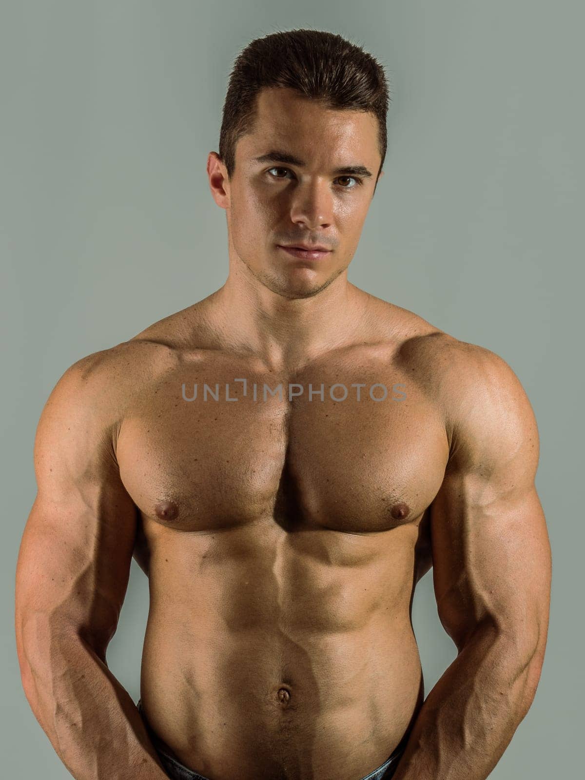 Shirtless young male bodybuilder in studio portrait by artofphoto