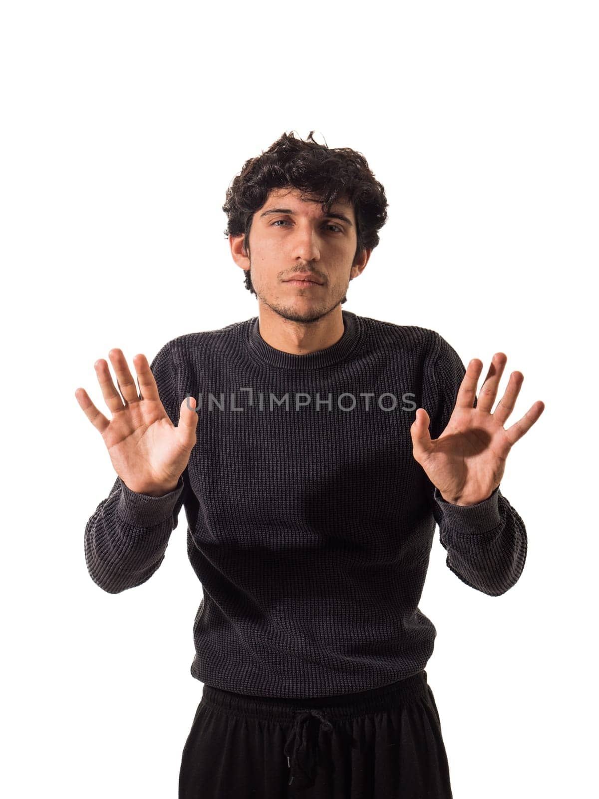 A man in a black sweater is holding his hands up, isolated on white background in studio shot