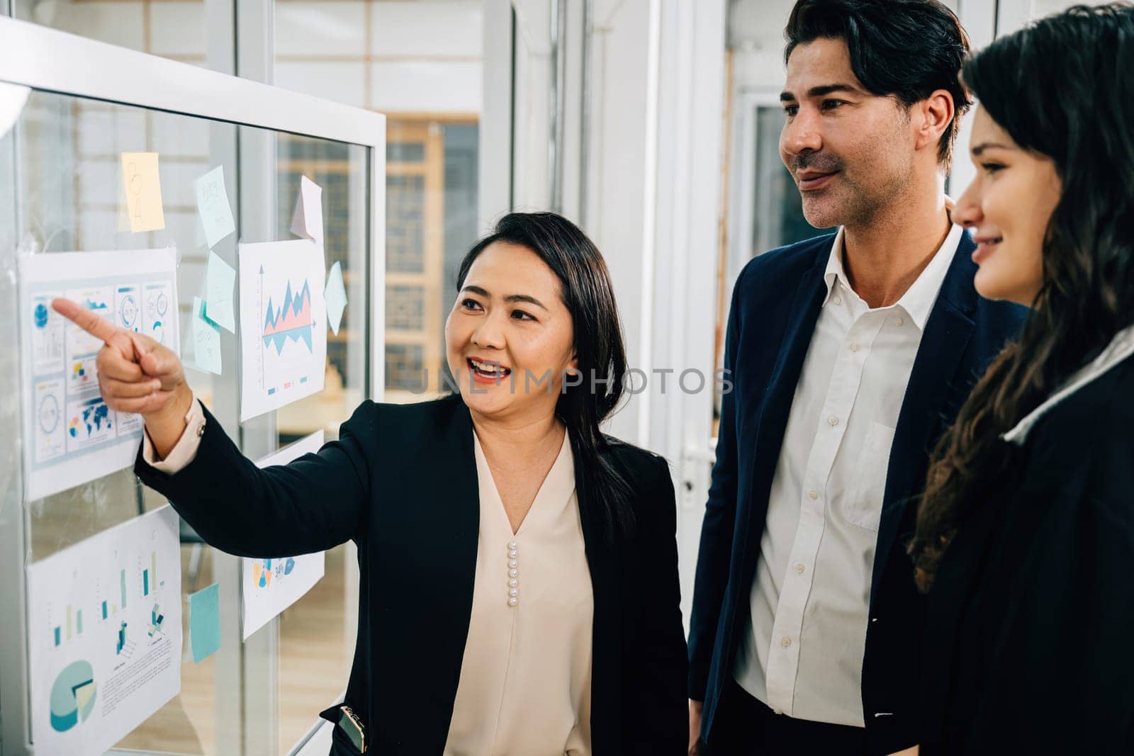 Colleagues from diverse ethnic backgrounds gather for a meeting around a whiteboard, discussing ideas, strategies, and goals. Emphasizing effective collaboration, leadership, and cooperation. by Sorapop