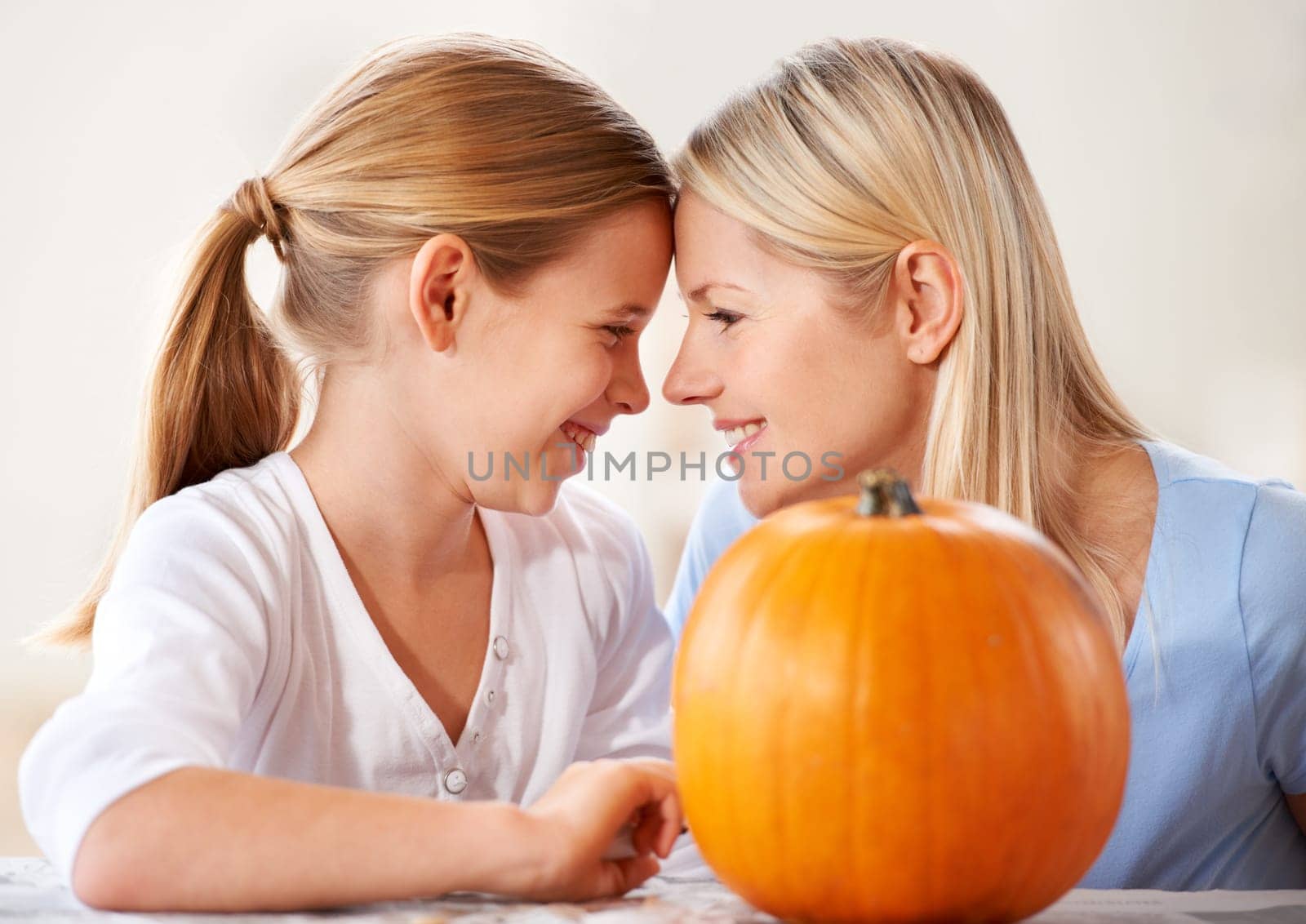 Mother, daughter or happy and pumpkin for halloween, celebration or decoration in kitchen of apartment or home. Family, face or smile and vegetable for preparation, holiday or creative event in house.