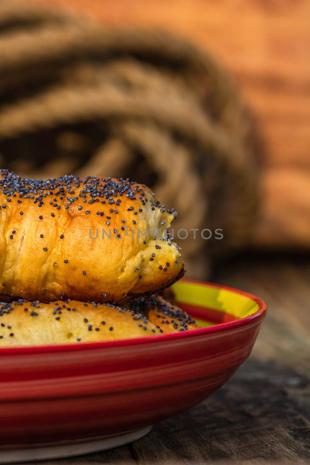 Sausages baked in dough sprinkled with salt and poppy seeds in a rustic composition. Sausages rolls, delicious homemade pastries.  by vladispas