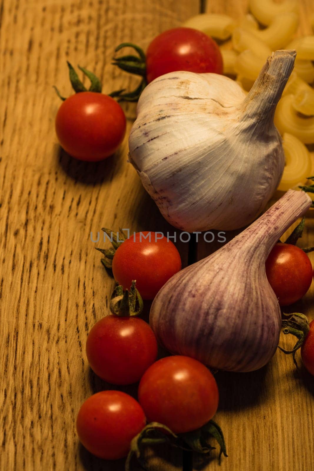 Cherry tomatoes, garlic and pasta on a wooden board. Food concept.