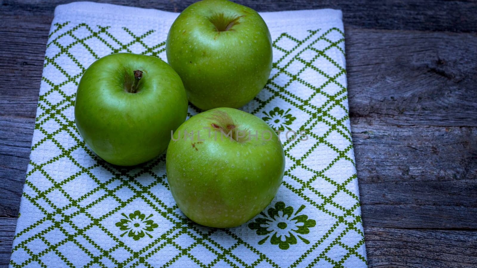  Ripe green apples on a rustic napkin on wooden table. by vladispas