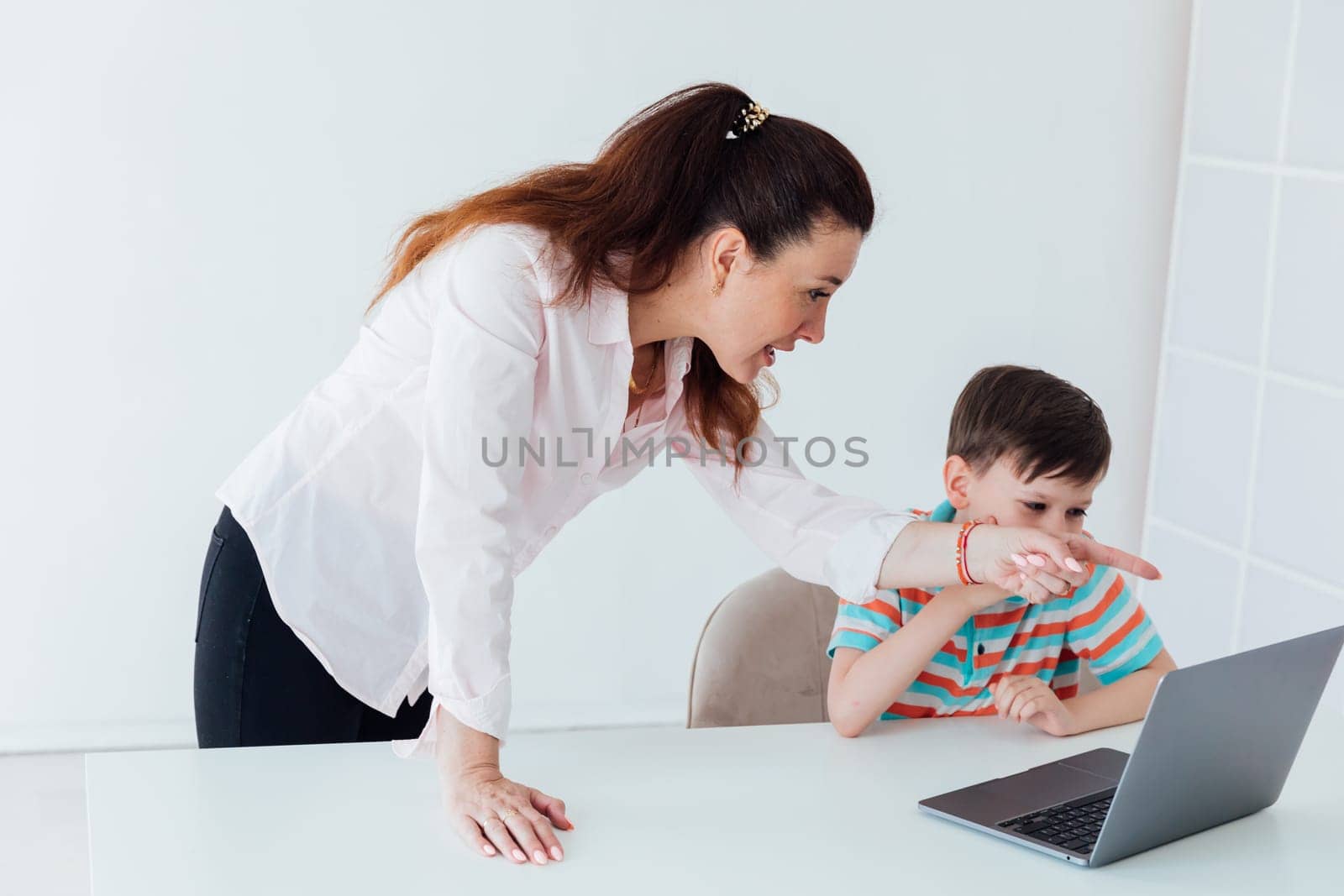 Female teacher teaches boy to work on computer online by Simakov