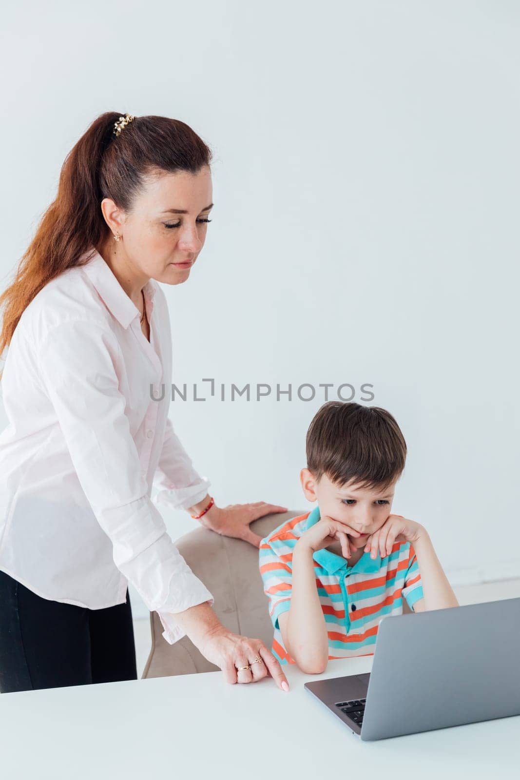 Female teacher teaches boy to work on computer online by Simakov