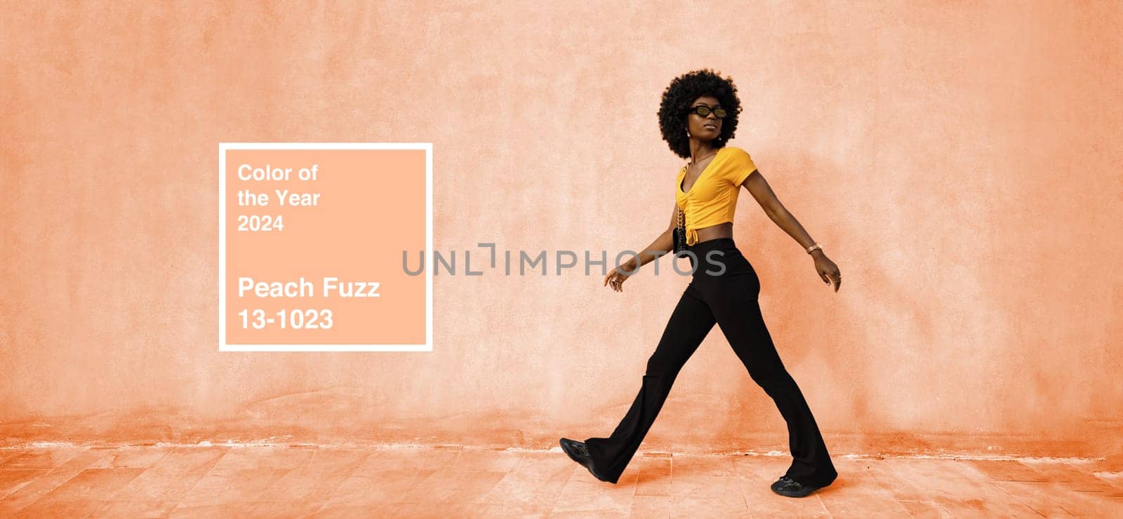 African woman model posing near the wall of Peach fuzz color of the Year 2024 concept