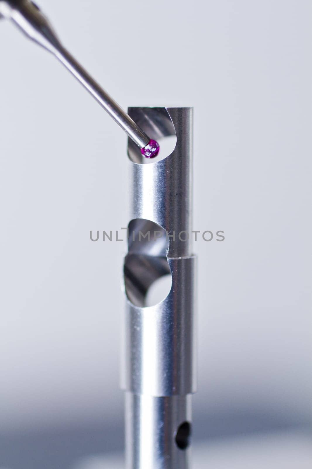 Pink probe of CMM checks metal part with actue precision for faults and flaws.