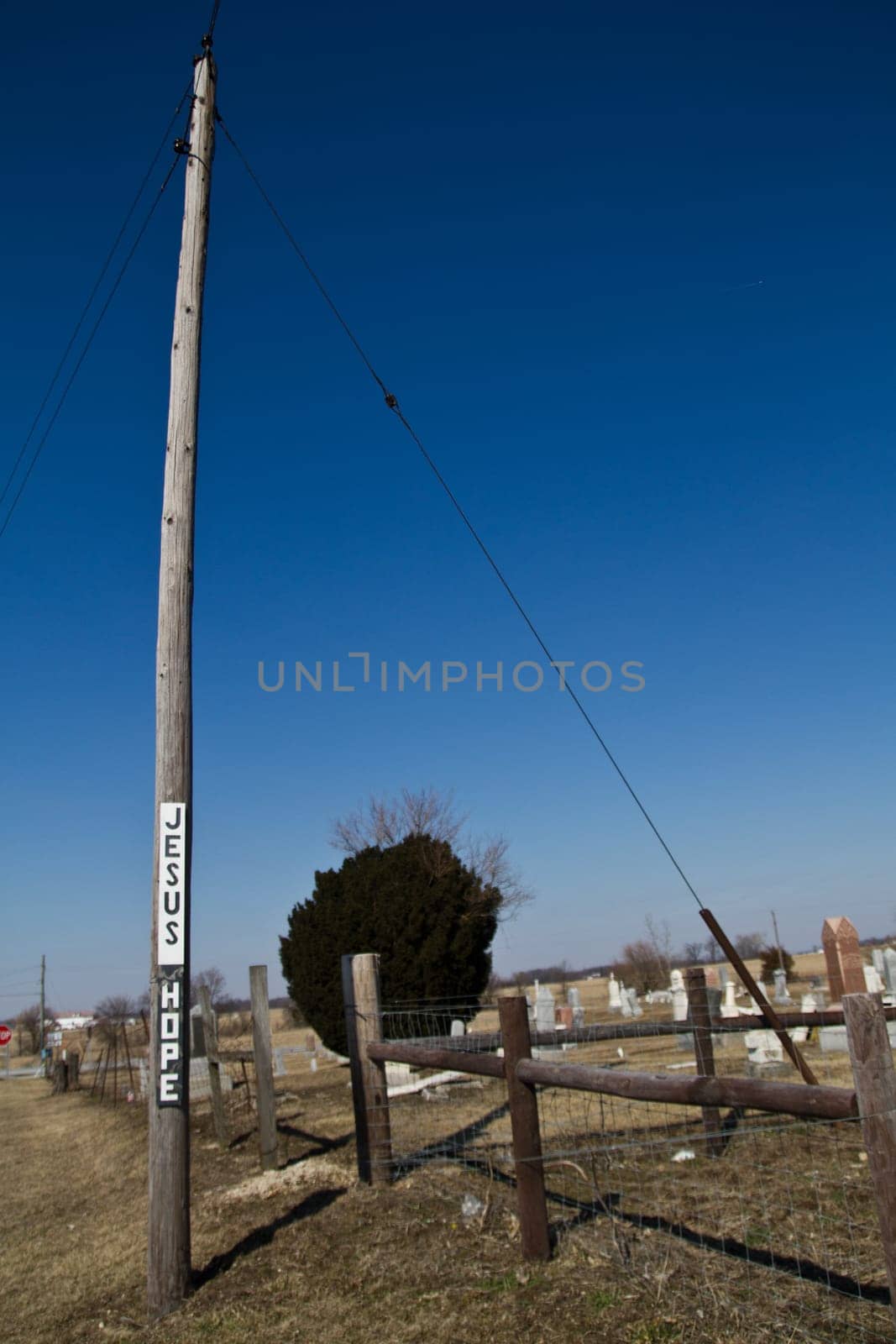 Rural Spirituality - Jesus Hope Signs on Utility Pole against Cemetery Backdrop by njproductions