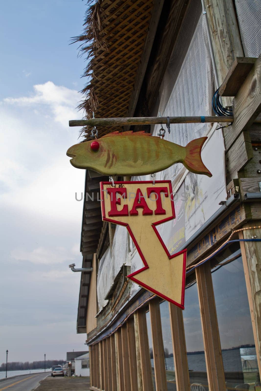 Colorful fish sign points the way to a rustic lakeside restaurant in Indiana, inviting diners to enjoy a leisurely seafood feast by the water.
