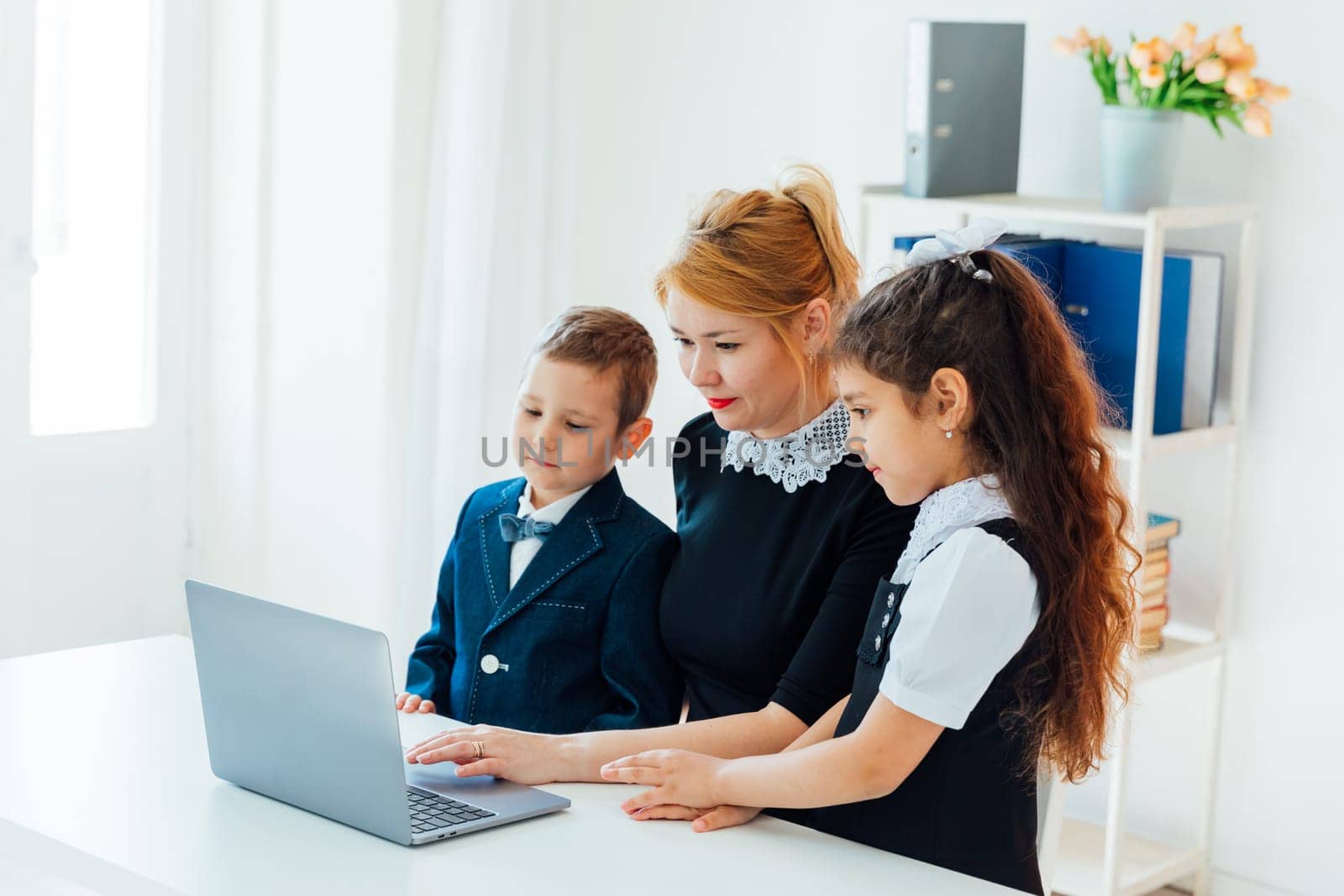 Female teacher in lesson at school teaching children on laptop by Simakov
