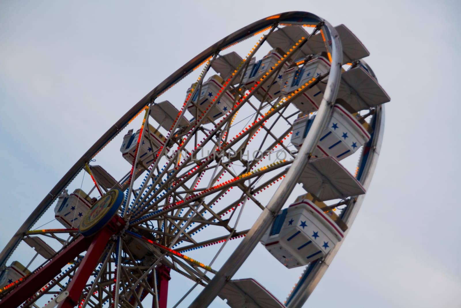 Experience the excitement of a vibrant Ferris wheel at twilight in Gatlinburg, Tennessee. This Americana-themed ride adorned with warm lights and starry gondolas invites you to enjoy the thrill of a fair.