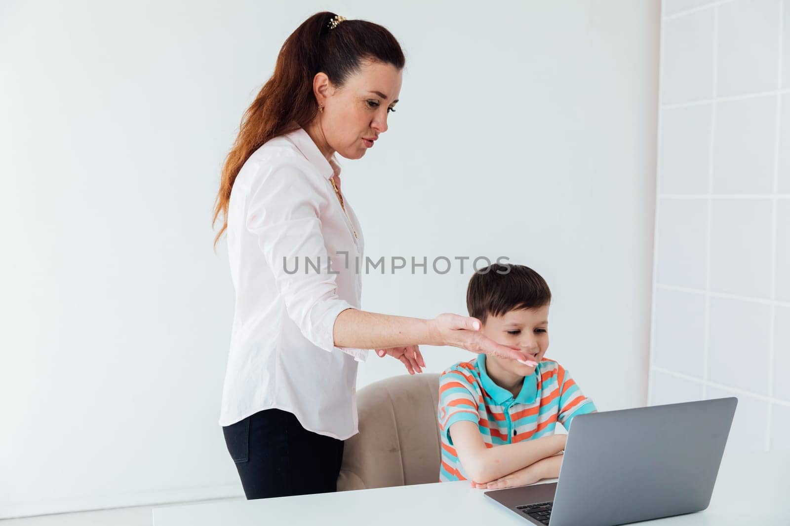 Female teacher teaches boy to work on computer online by Simakov