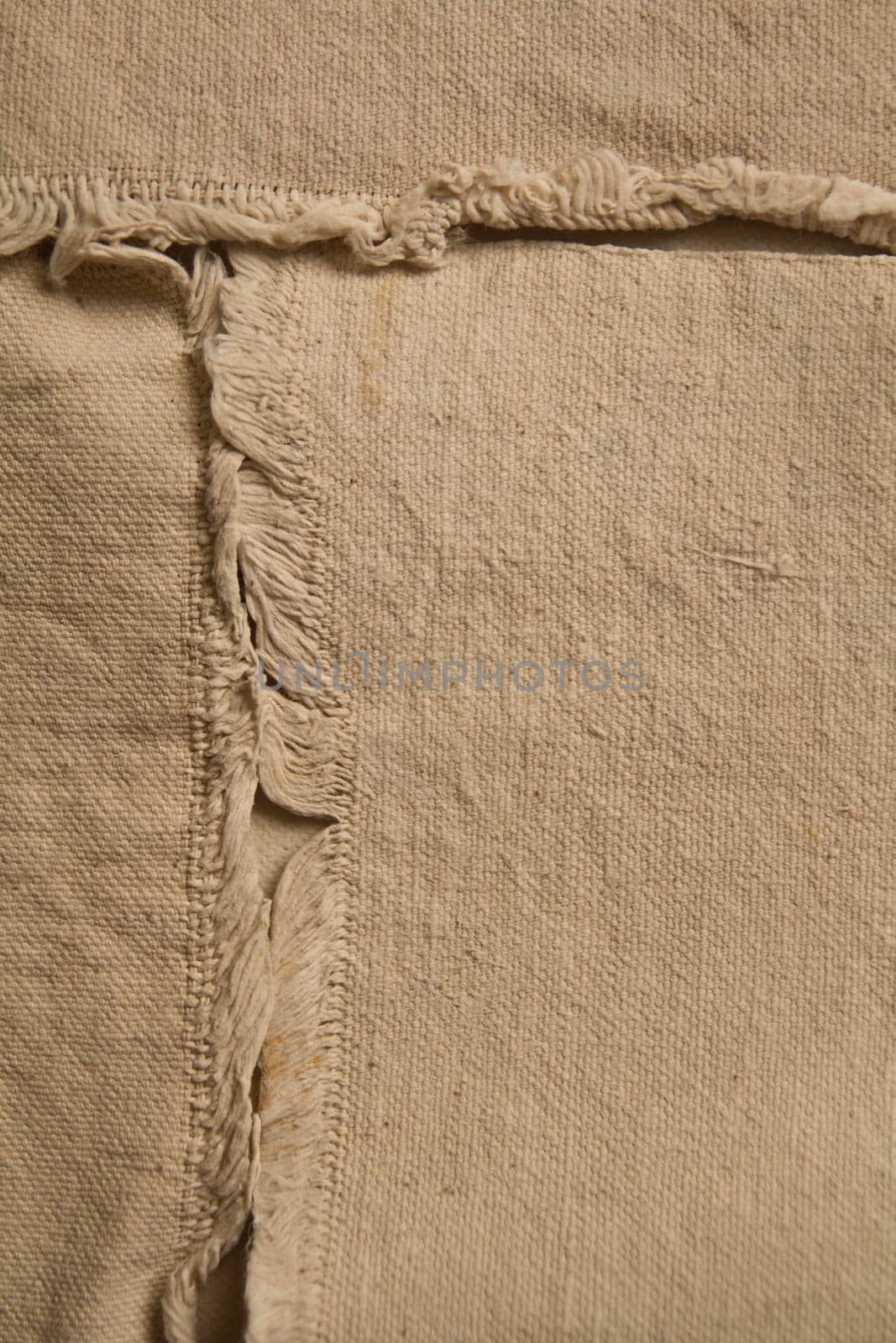 Close-Up of Beige Textured Fabric with Frayed Seam Detail by njproductions