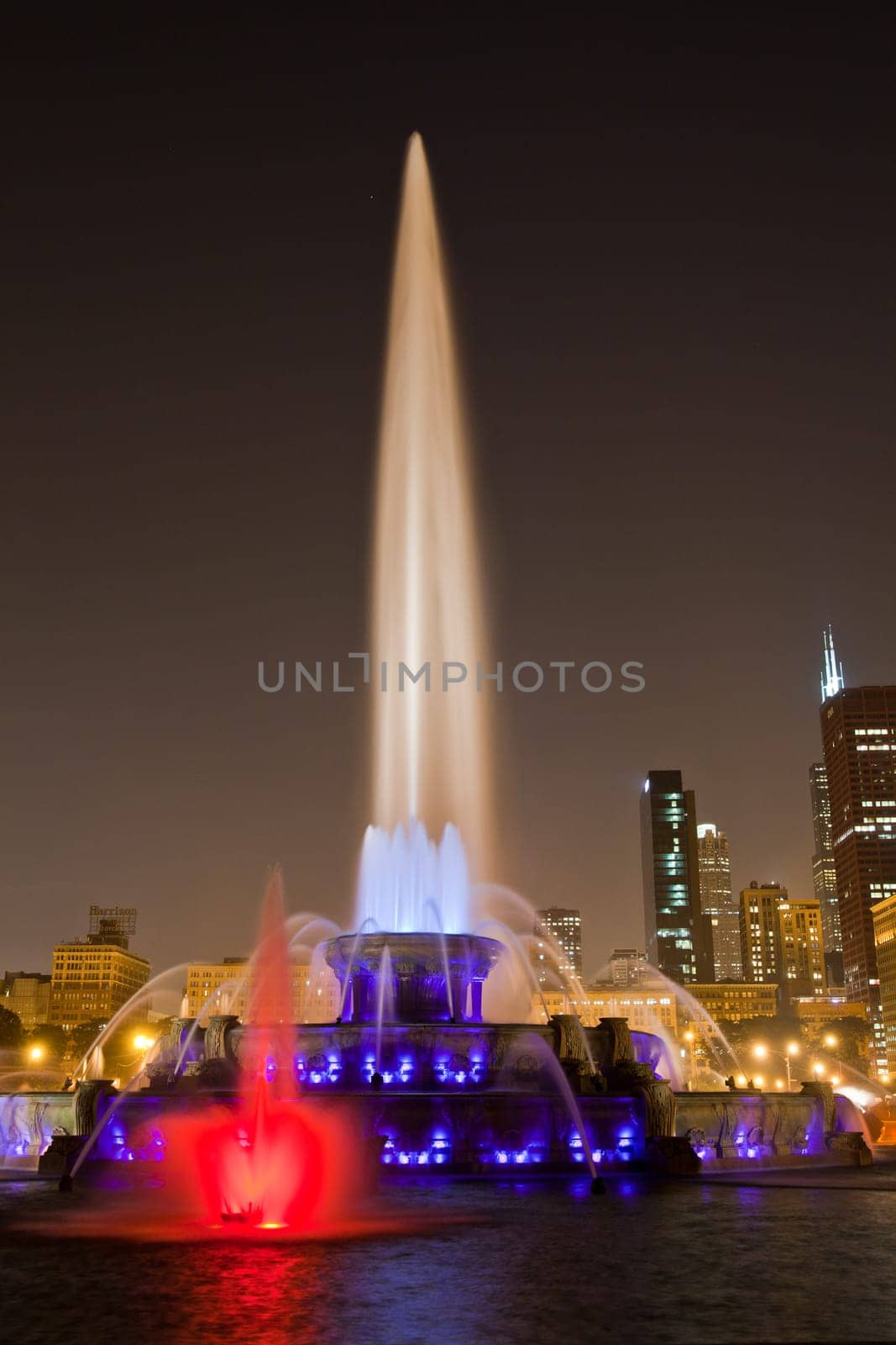 Nighttime Splendor: Vibrant cityscape of Chicago, Illinois, showcases a majestic illuminated fountain against a backdrop of illuminated buildings, capturing the beauty of urban life at night.