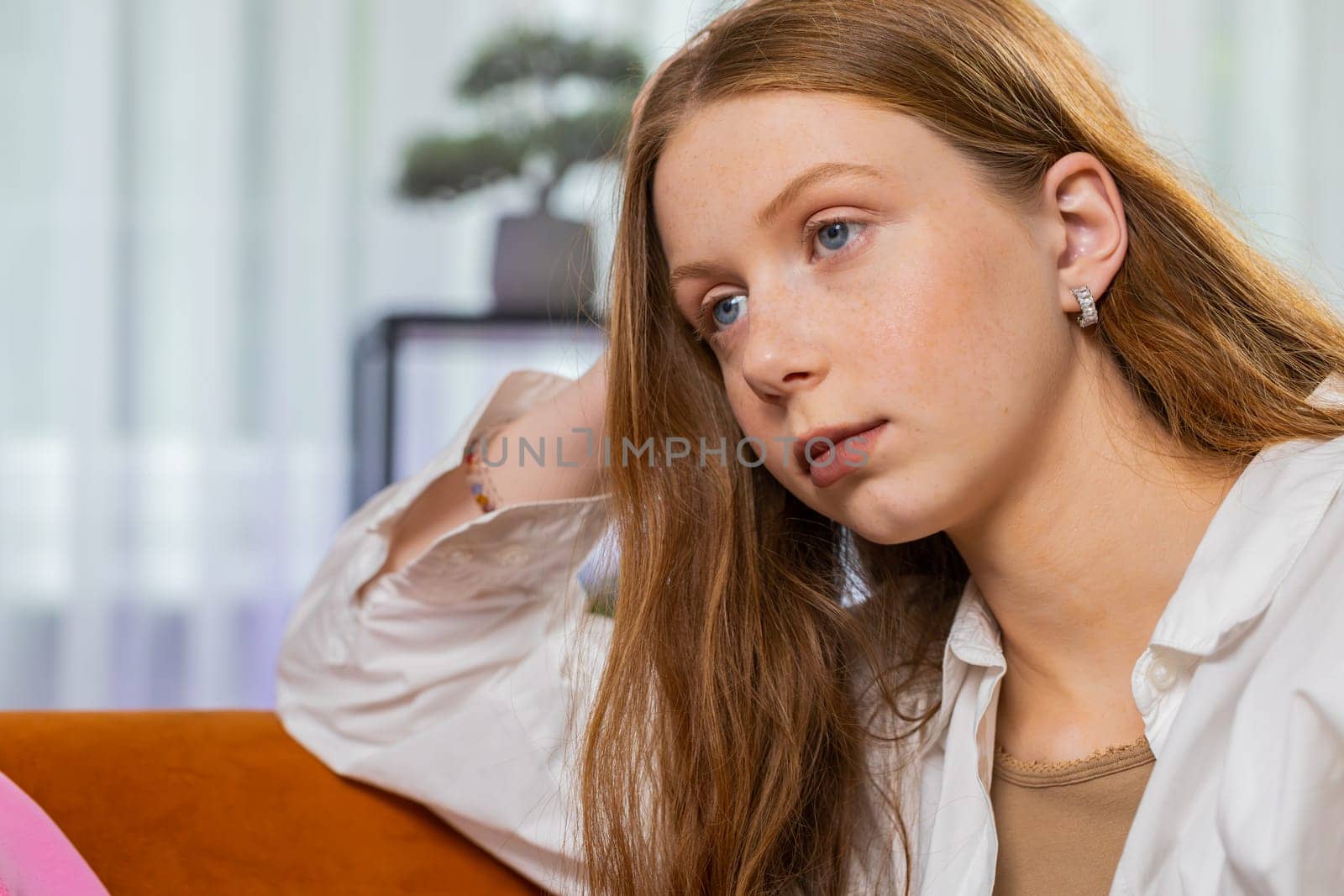 Sad lonely teenager girl sits at home room looks pensive thinks over life concerns or unrequited love suffers from unfair situation. Alone child problem break up depressed feeling bad annoyed burnout