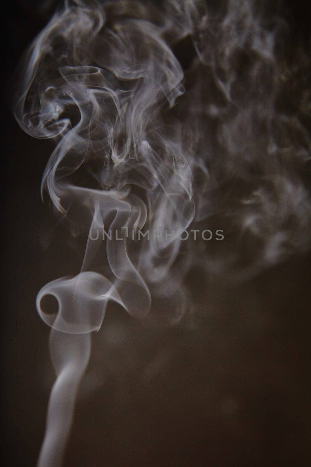 Captivating ethereal smoke gracefully swirls against a dark backdrop, creating an intriguing, mysterious atmosphere. Perfect for evoking creativity, transformation, and the intangible.