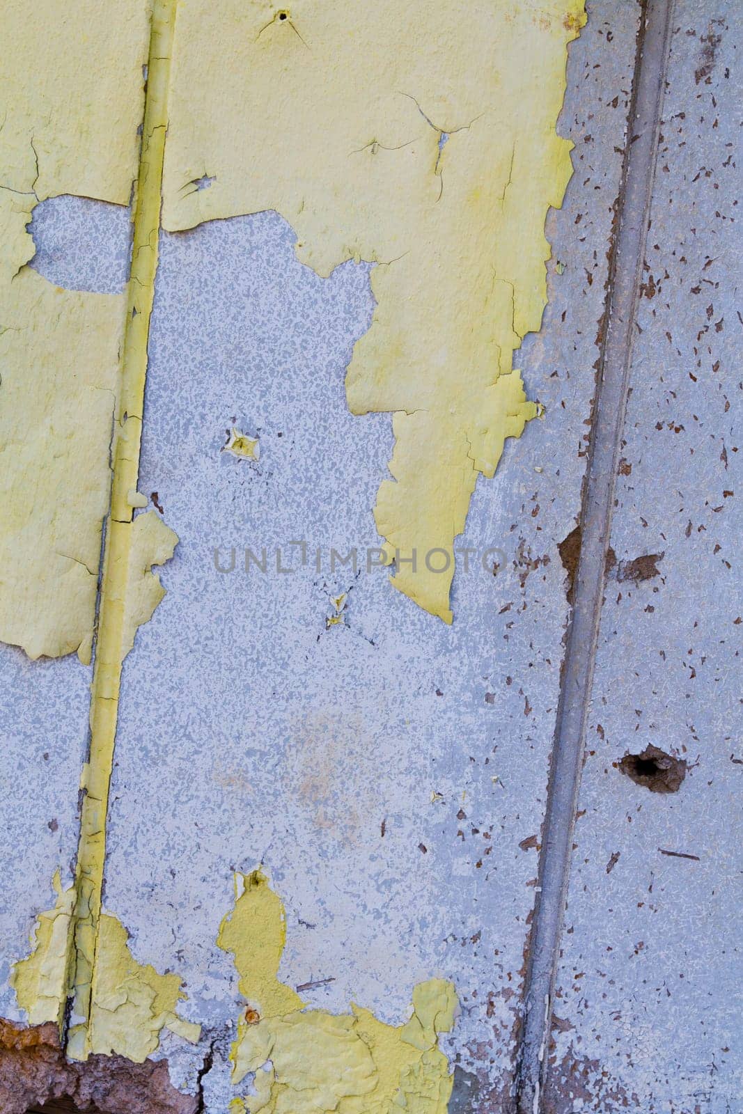 Urban Decay: Close-up view of deteriorating yellow paint reveals layers of history and wear. Rusty metal strip adds industrial charm. St. Louis, Missouri.