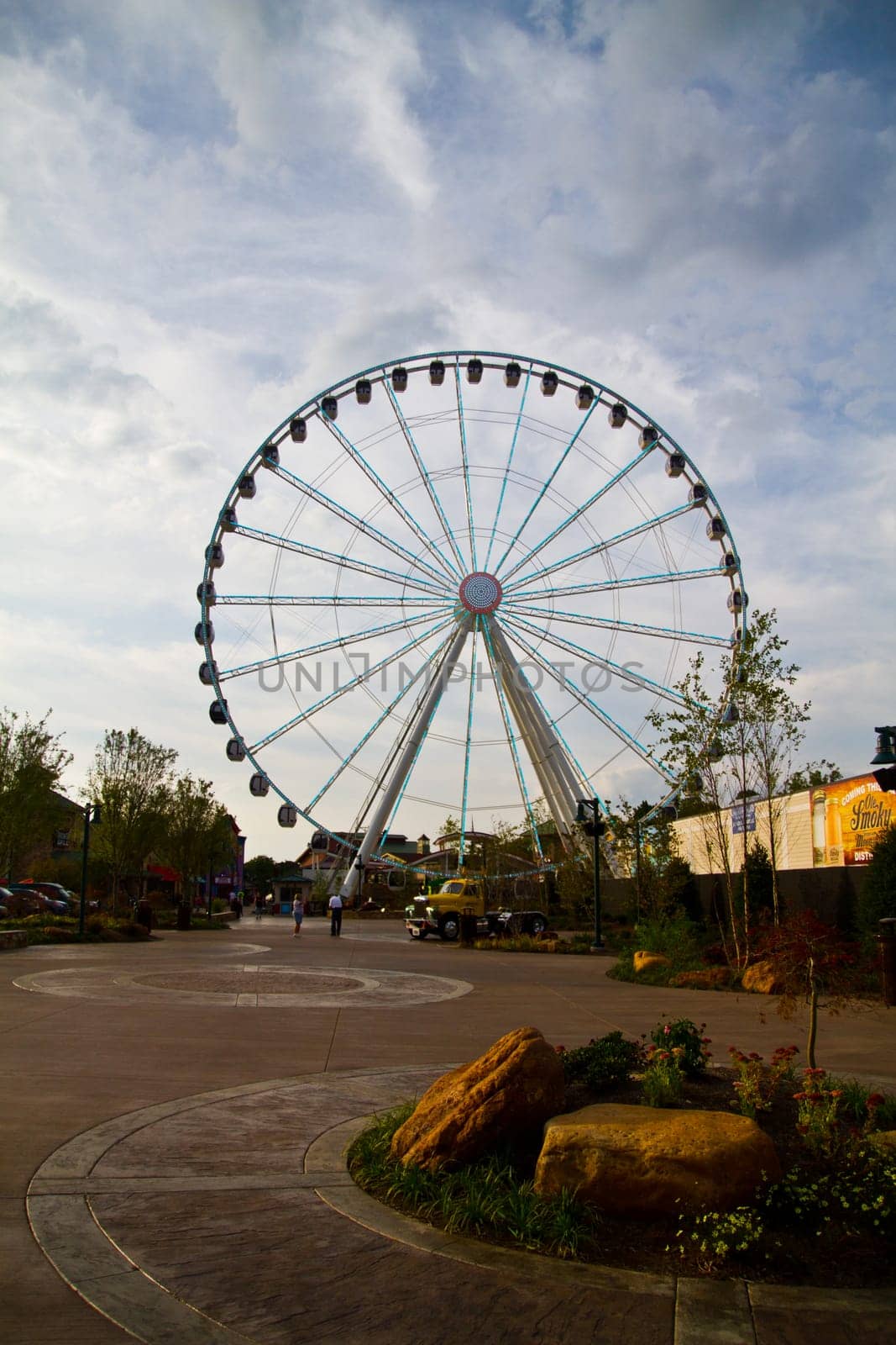 Experience the thrill of a towering Ferris wheel in Gatlinburg, Tennessee's lively leisure park. This iconic landmark offers family-friendly entertainment and breathtaking views against a partly cloudy sky.